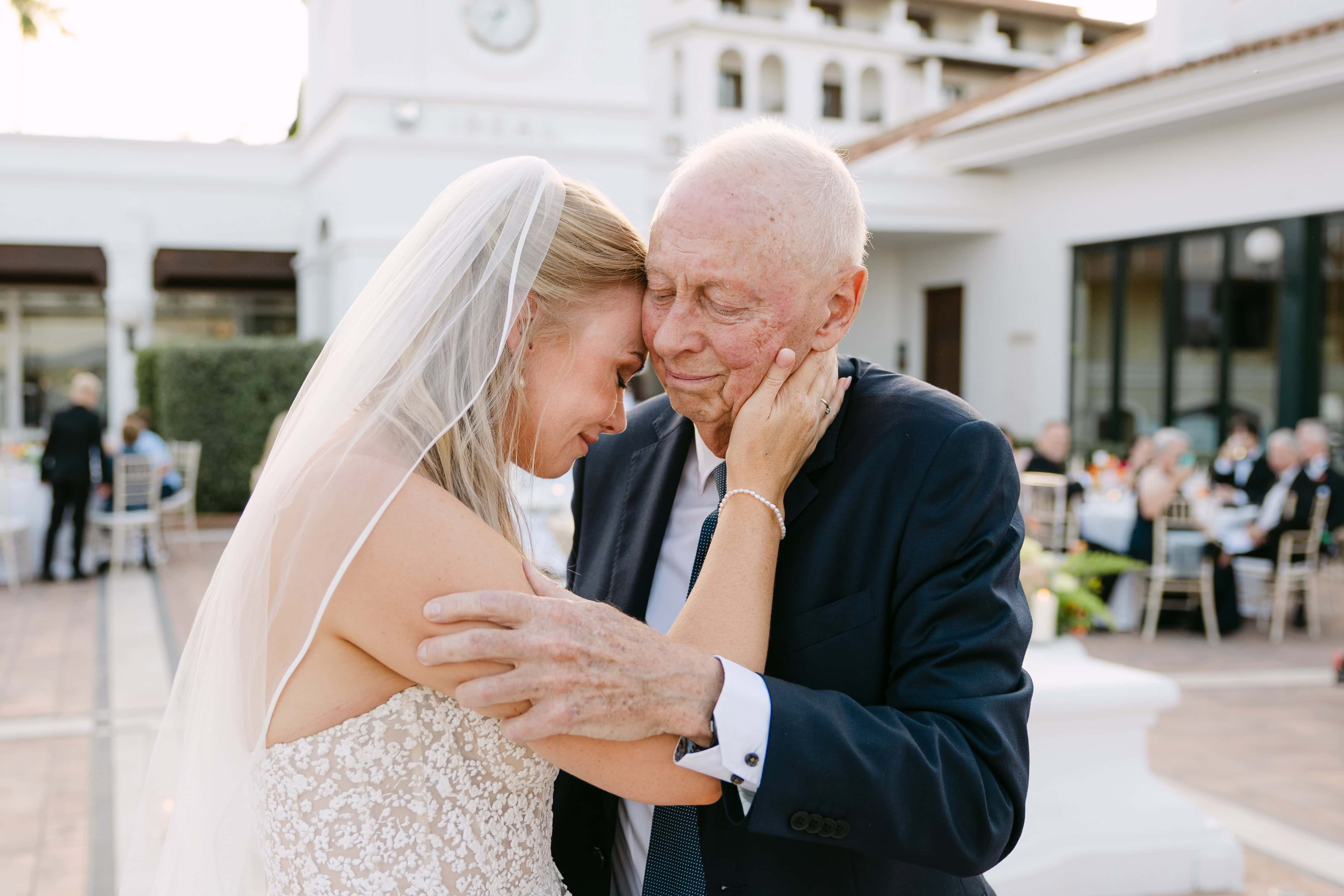 Bride embracing elderly man at outdoor wedding