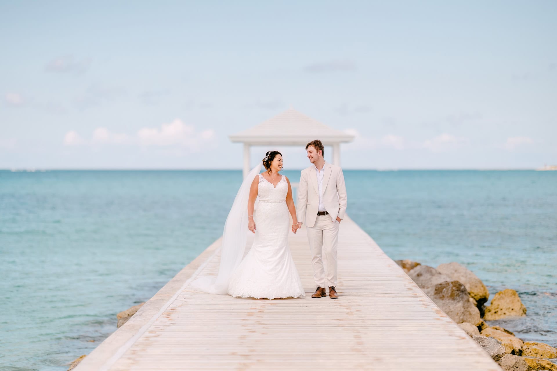 Bride and groom walking on seaside pier