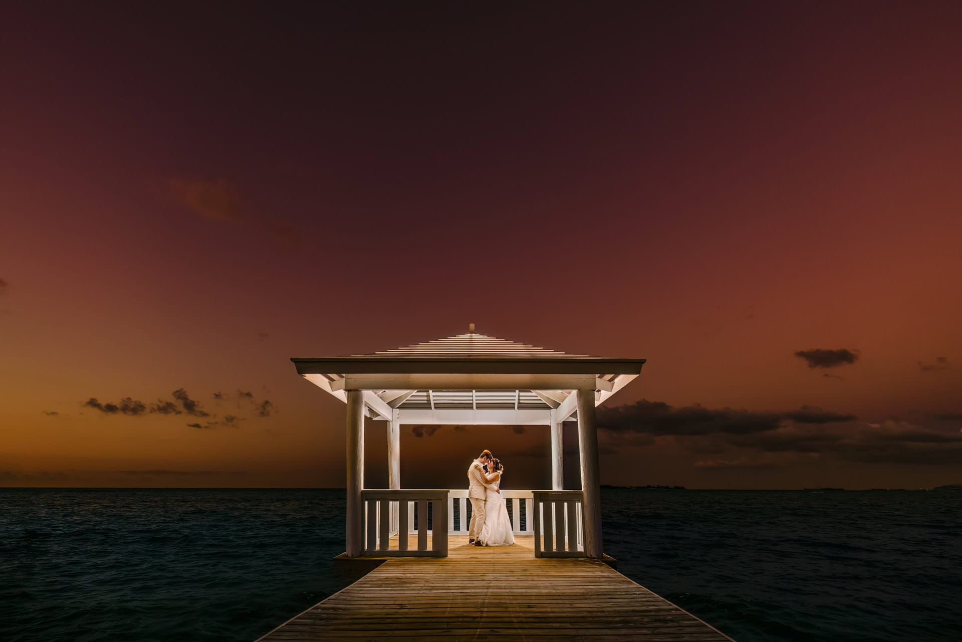Bride and groom embracing at sunset gazebo