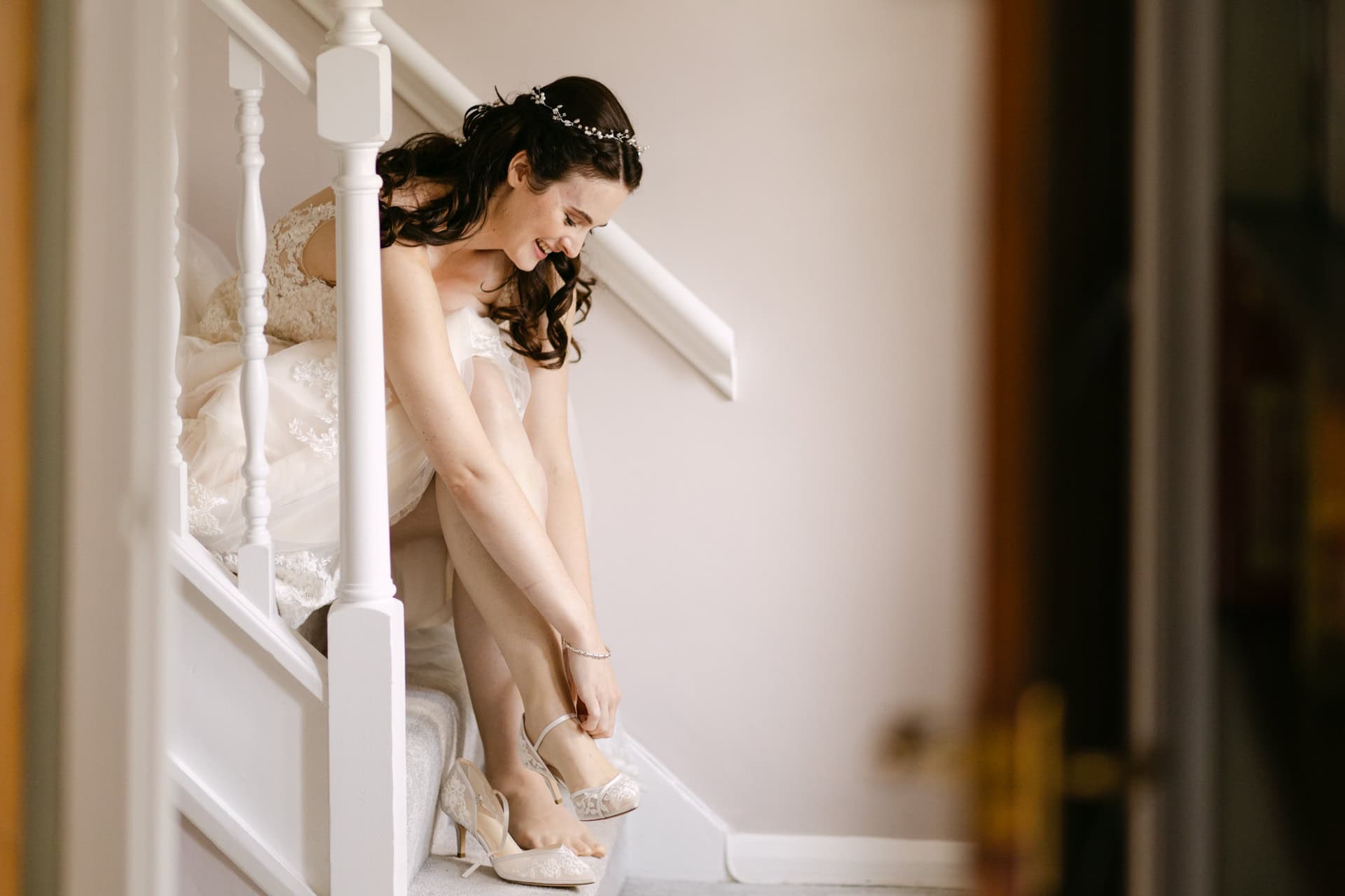 Bride sitting on stairs putting on wedding shoes