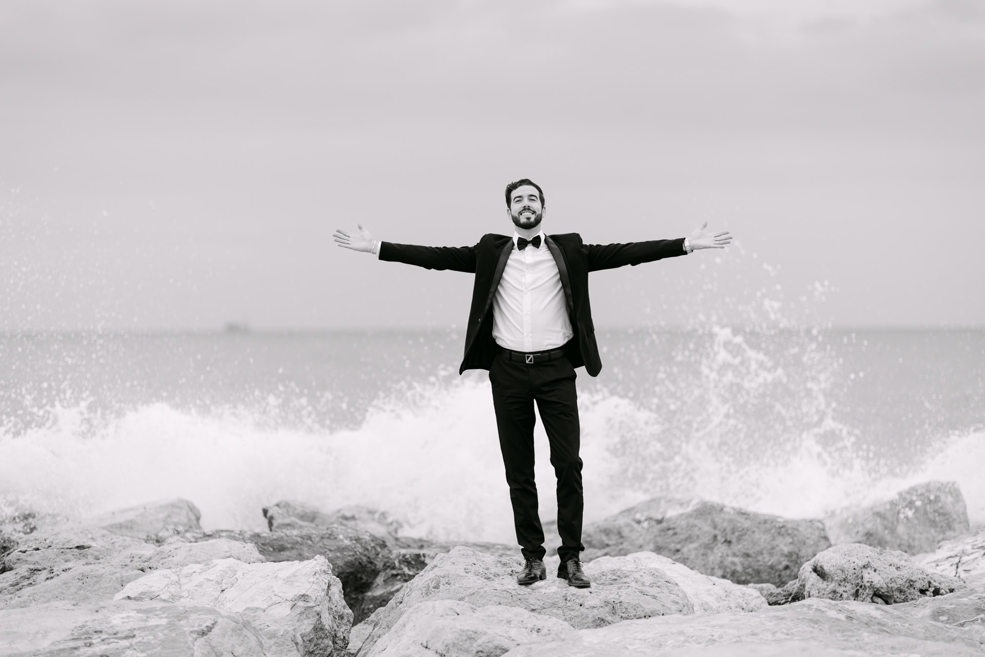 Man in tuxedo on rocks by sea