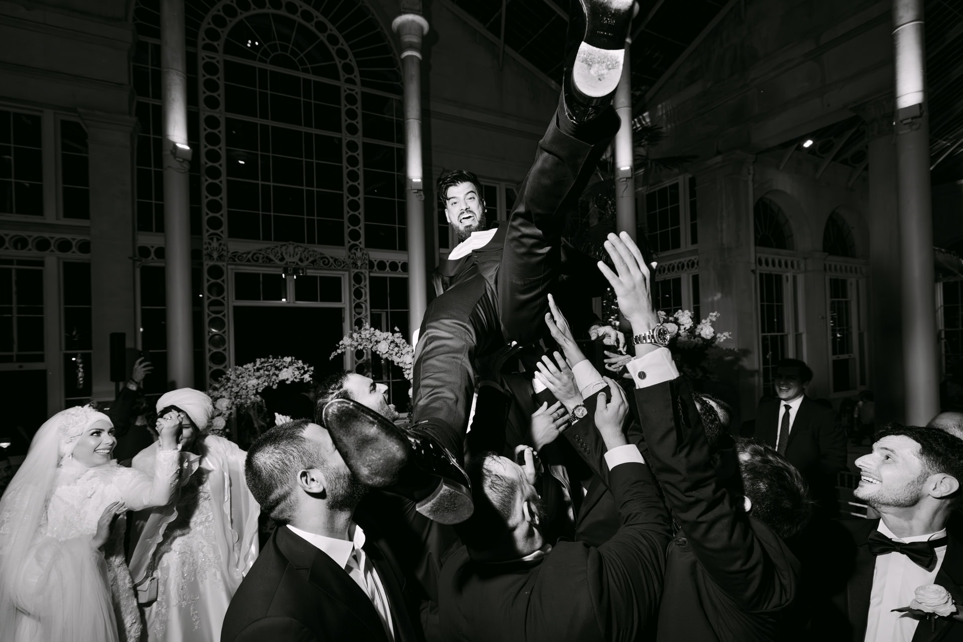 Groom lifted in air at wedding celebration