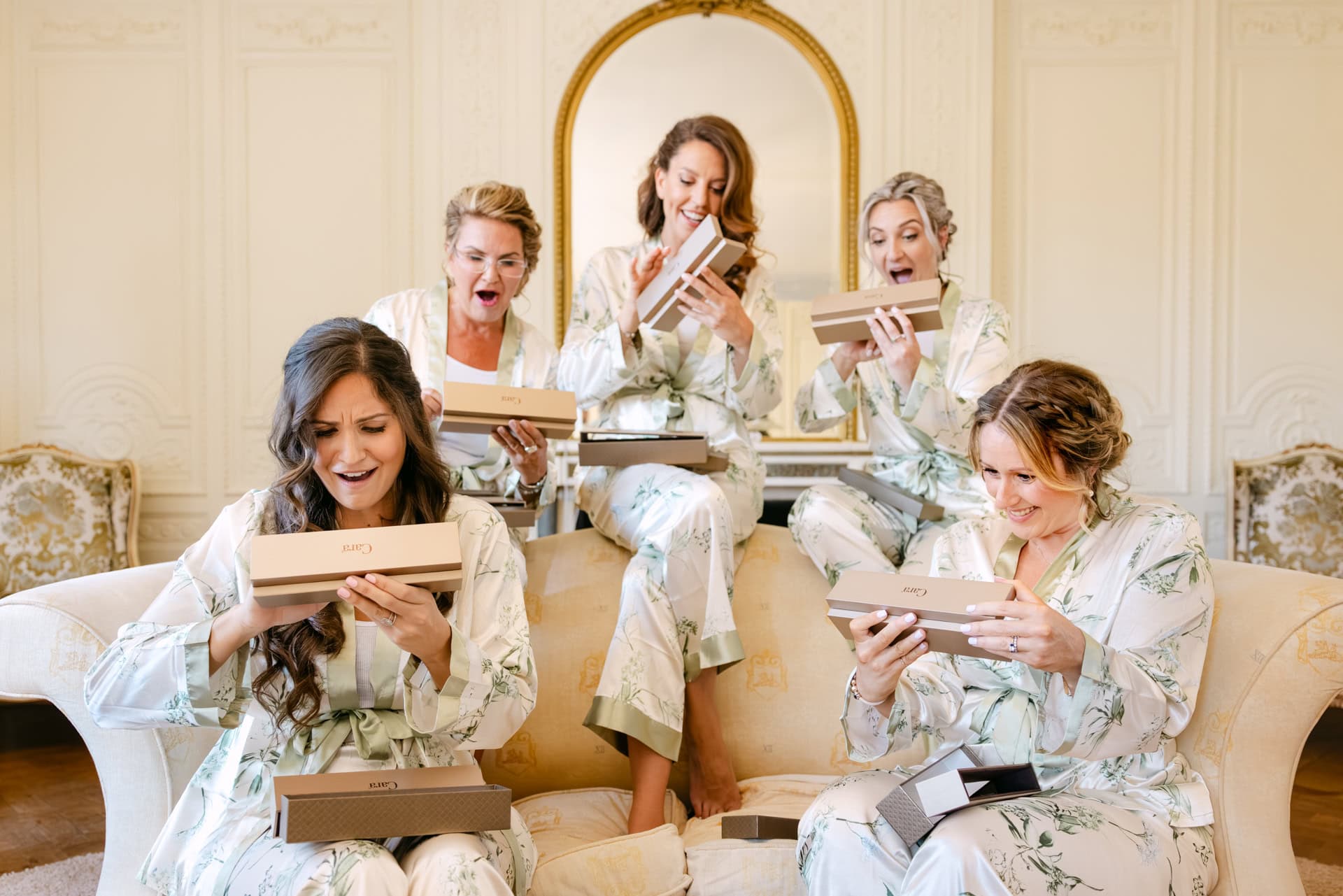 Bridesmaids opening gift boxes in matching robes