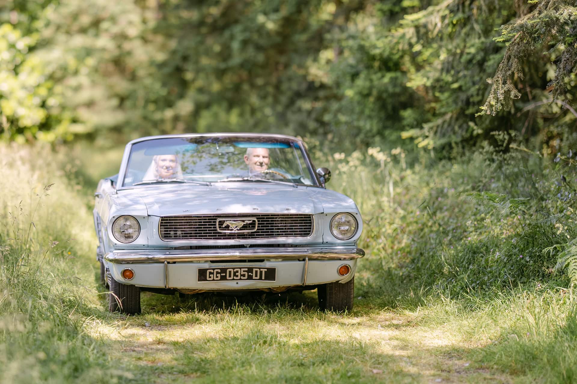 Vintage Ford Mustang convertible on grassy woodland path