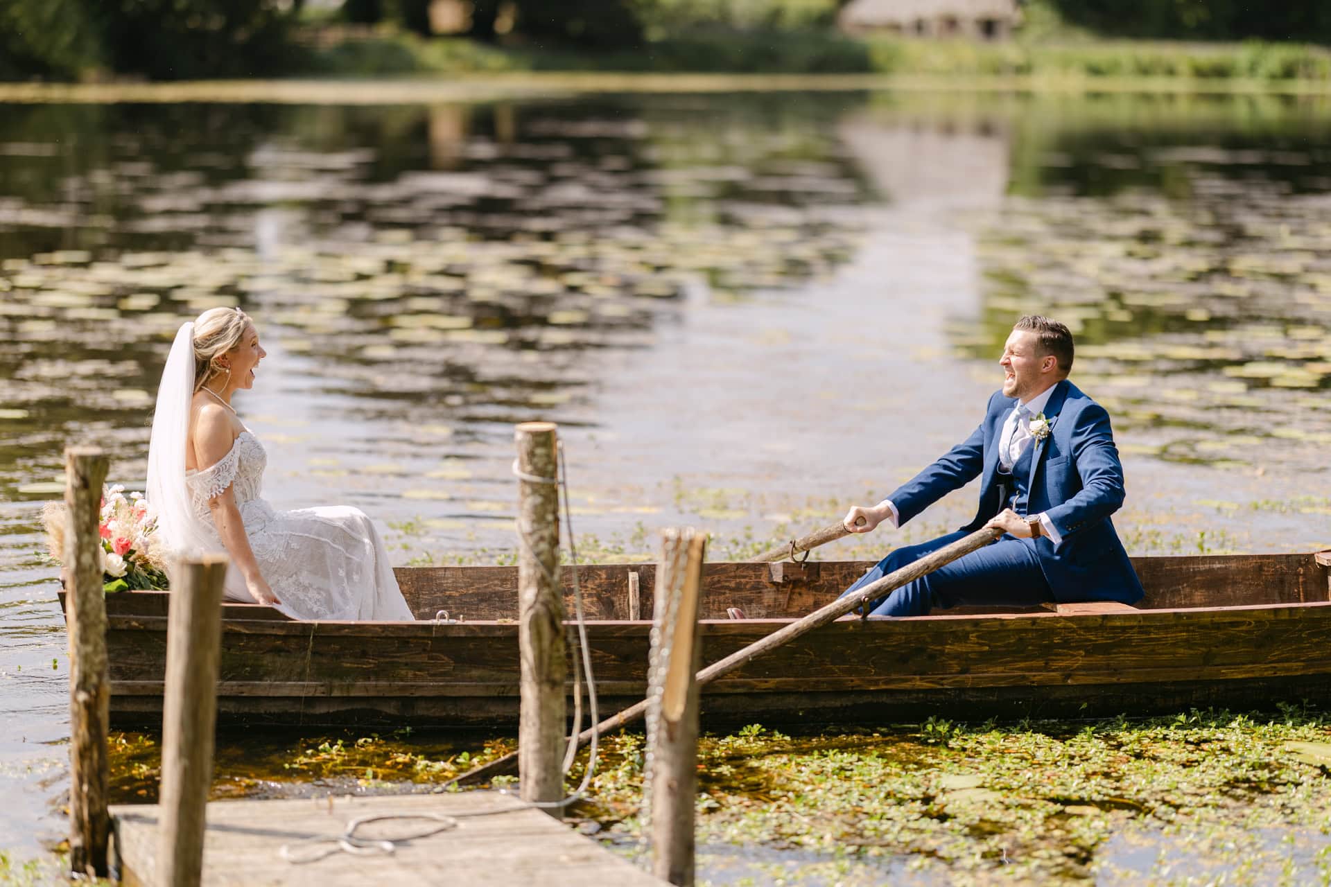Bride and groom rowing boat on lake