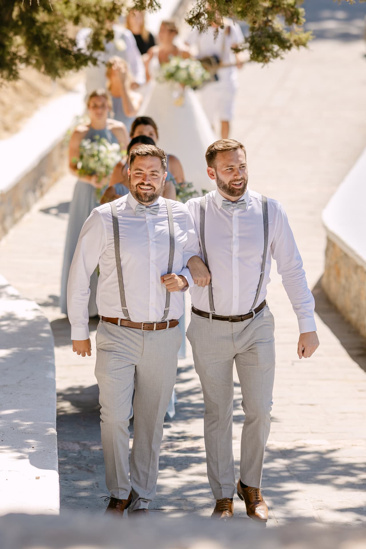 Two grooms walking arm in arm outdoors