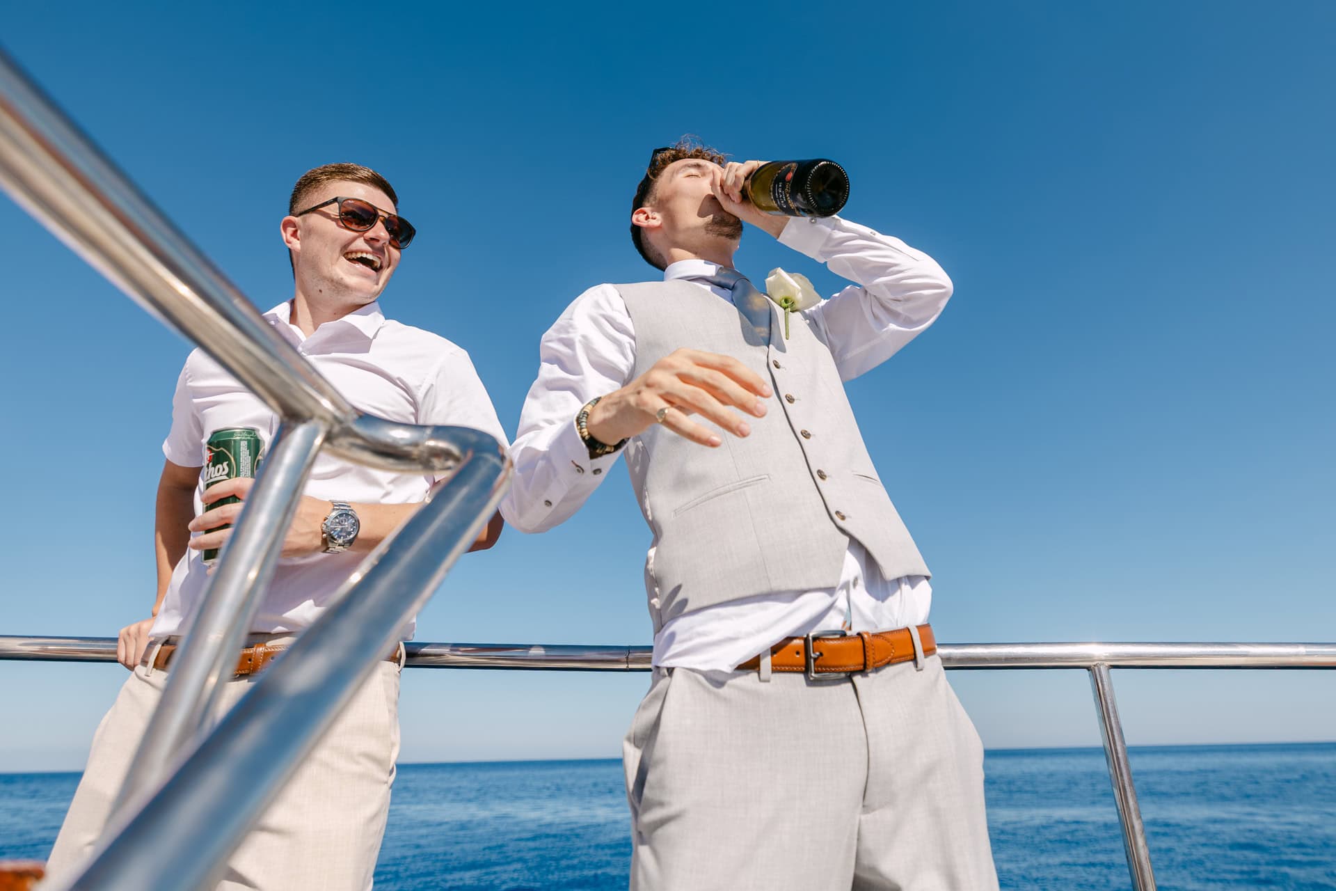 Two men celebrating on boat under blue sky