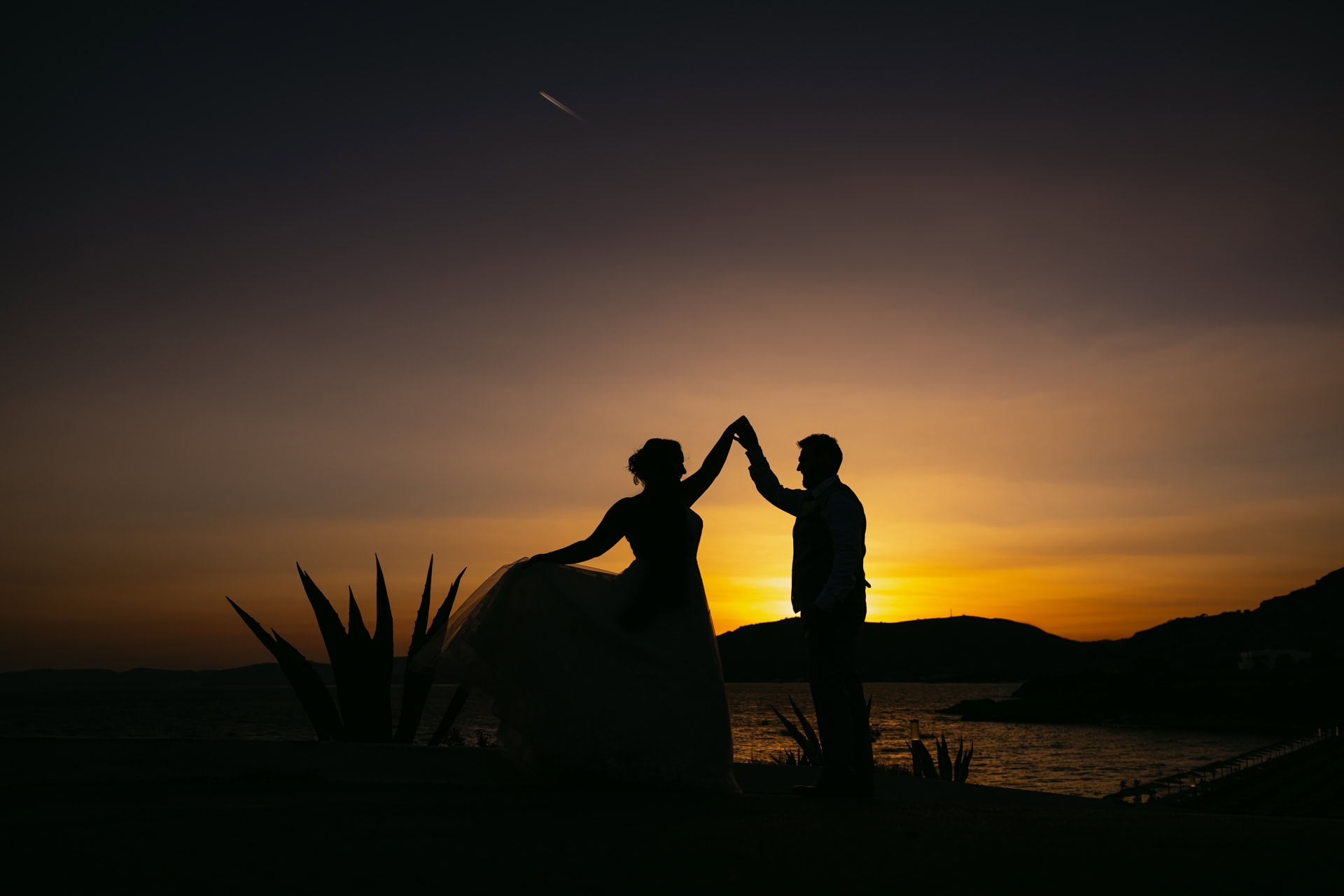 Silhouetted couple dancing at sunset by the sea