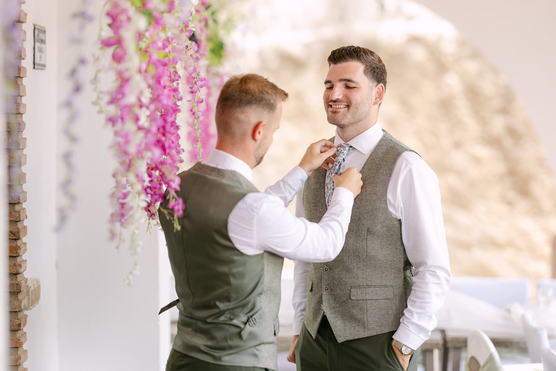 Man adjusting tie of groom at wedding venue