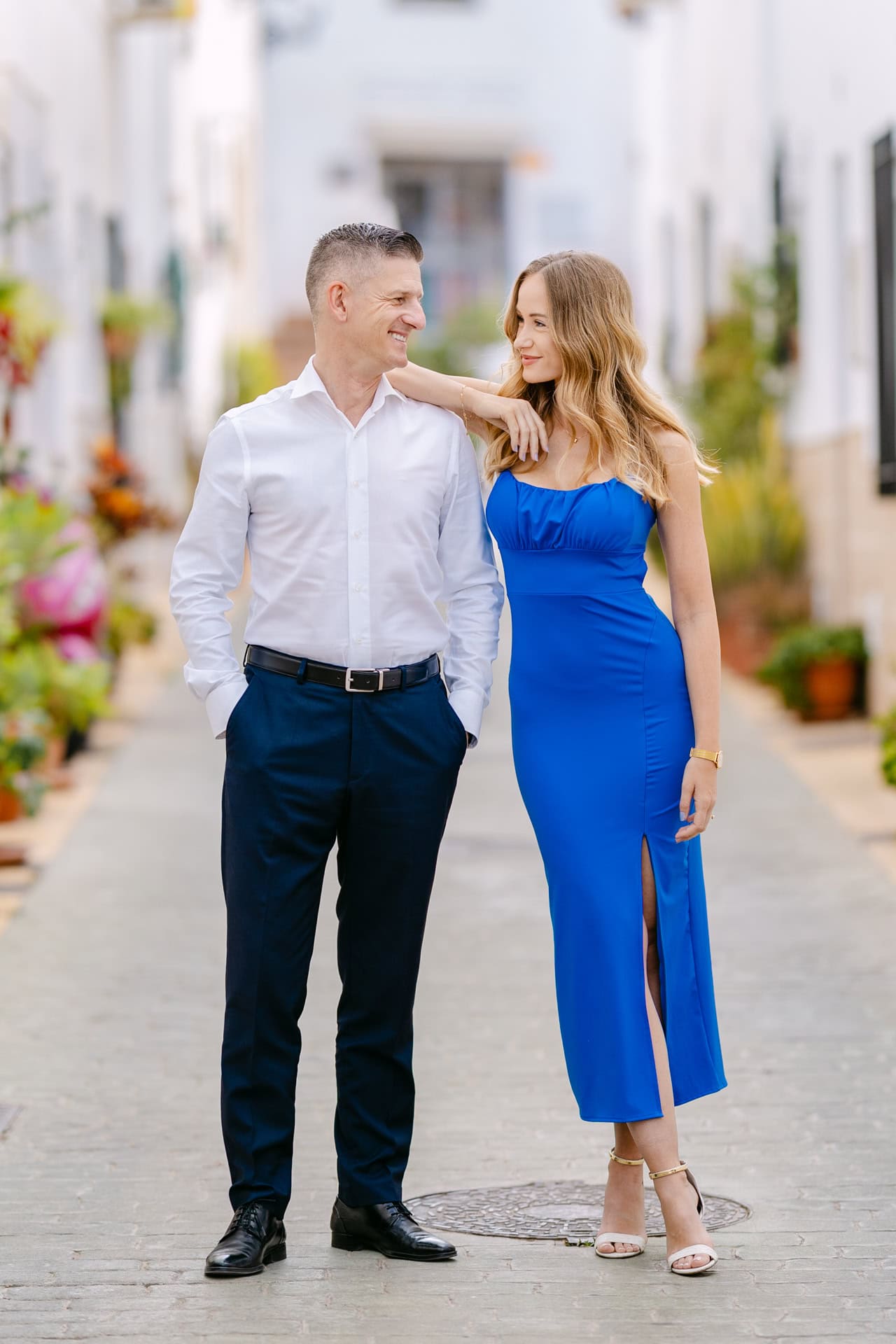 Smartly dressed couple walking along sunny street in Benalmadena Pueblo