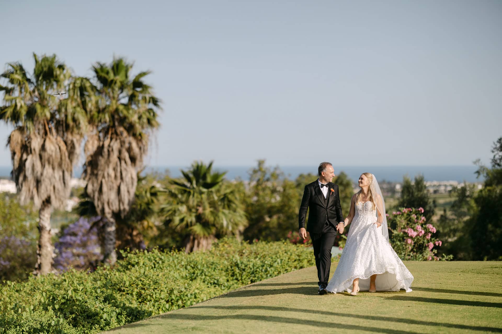 beautiful luxury Bride and groom walking on sunny garden lawn at the golf course in Westin la Quinta in Marbella Marriot wedding Venue