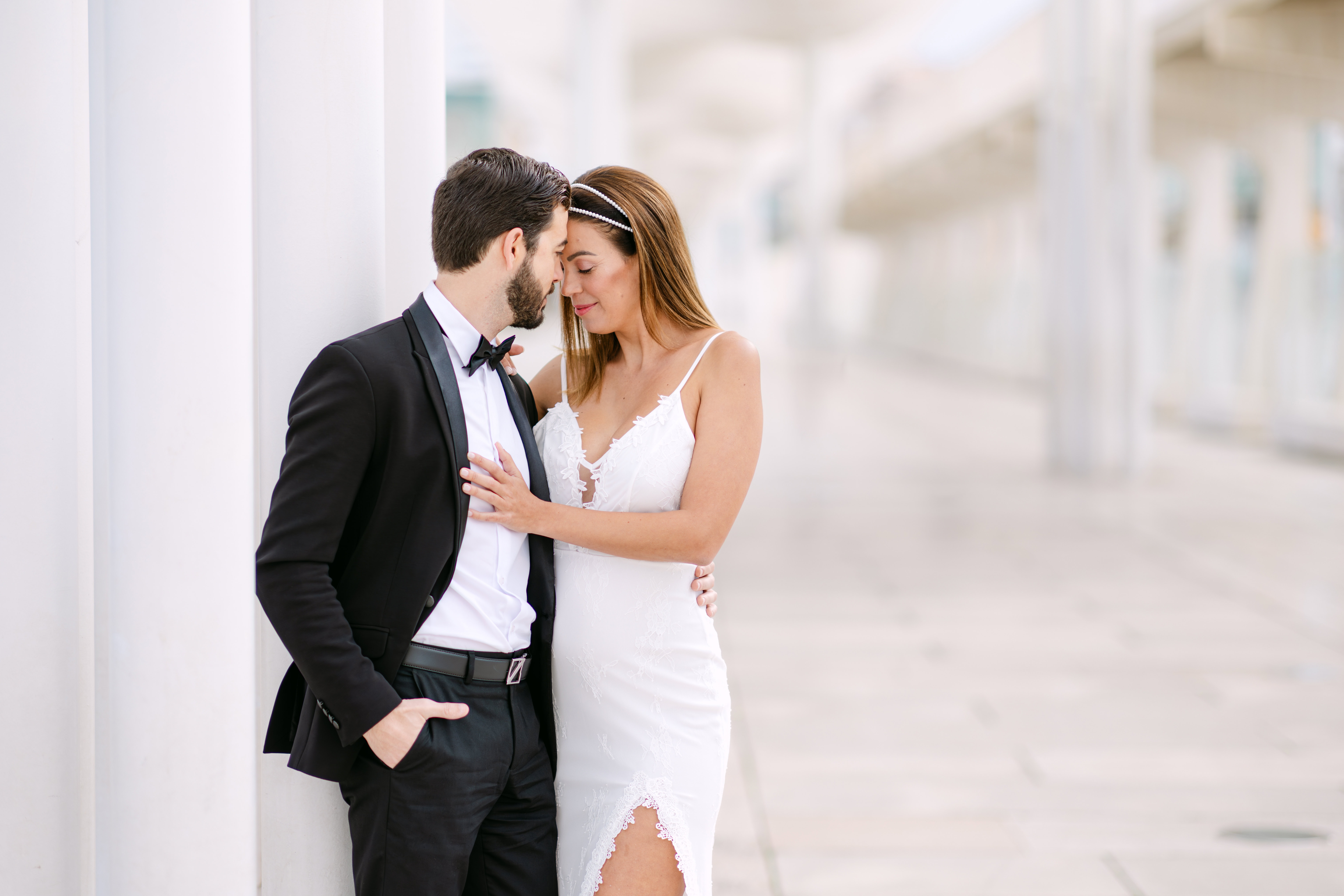 Bride and groom embracing by white columns in Malaga pier called El Palmeral de las Sorpresas