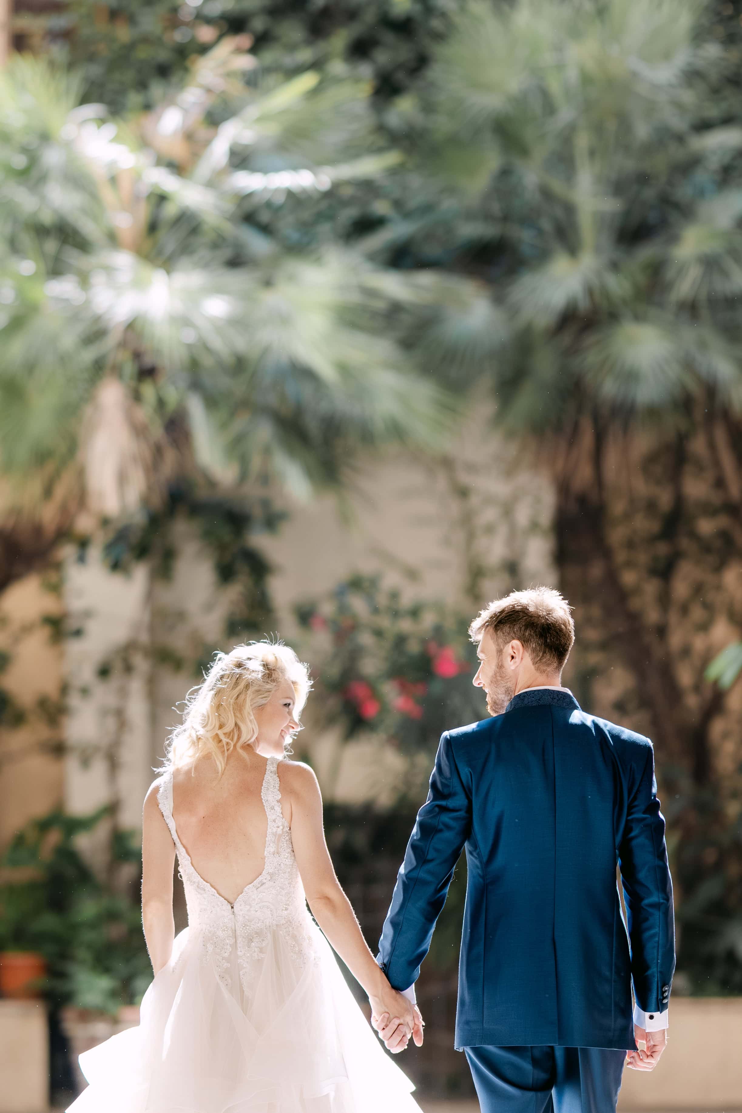 Bride and groom holding hands in sunny garden