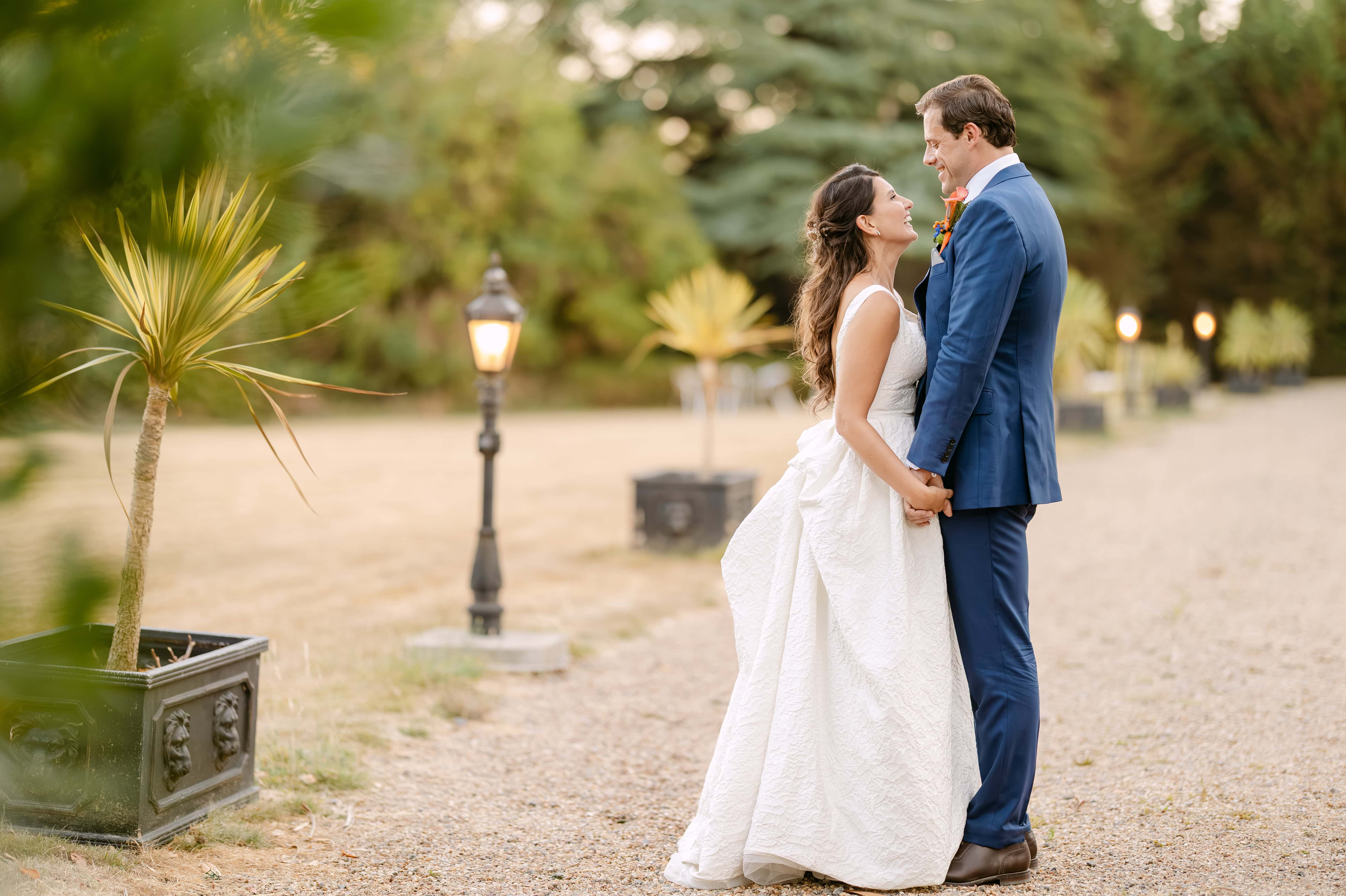 Bride and groom holding hands in garden and laughing during their wedding portait session in Finca La Concepcion in Malaga