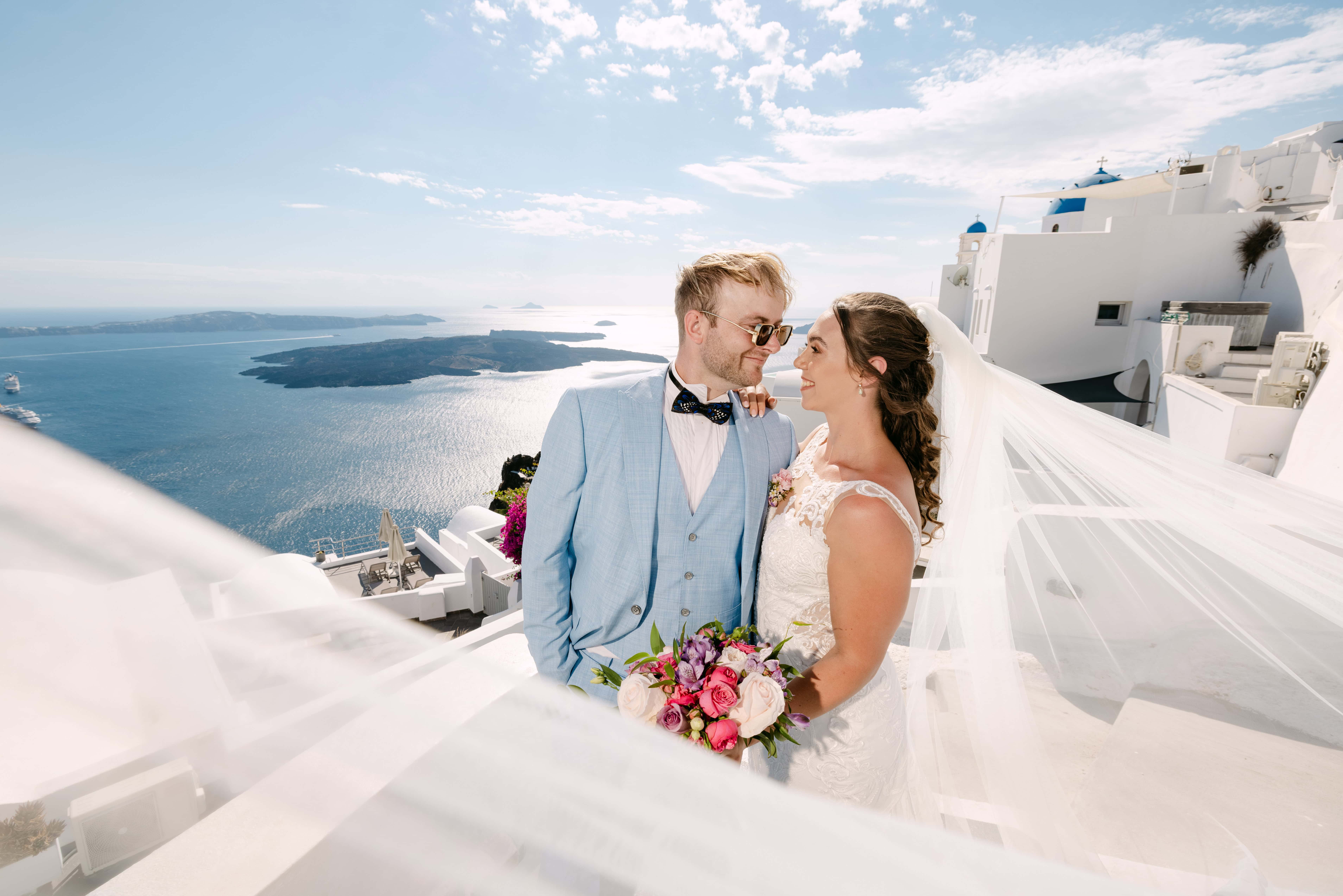 Bride and groom overlooking Santorini caldera coastline