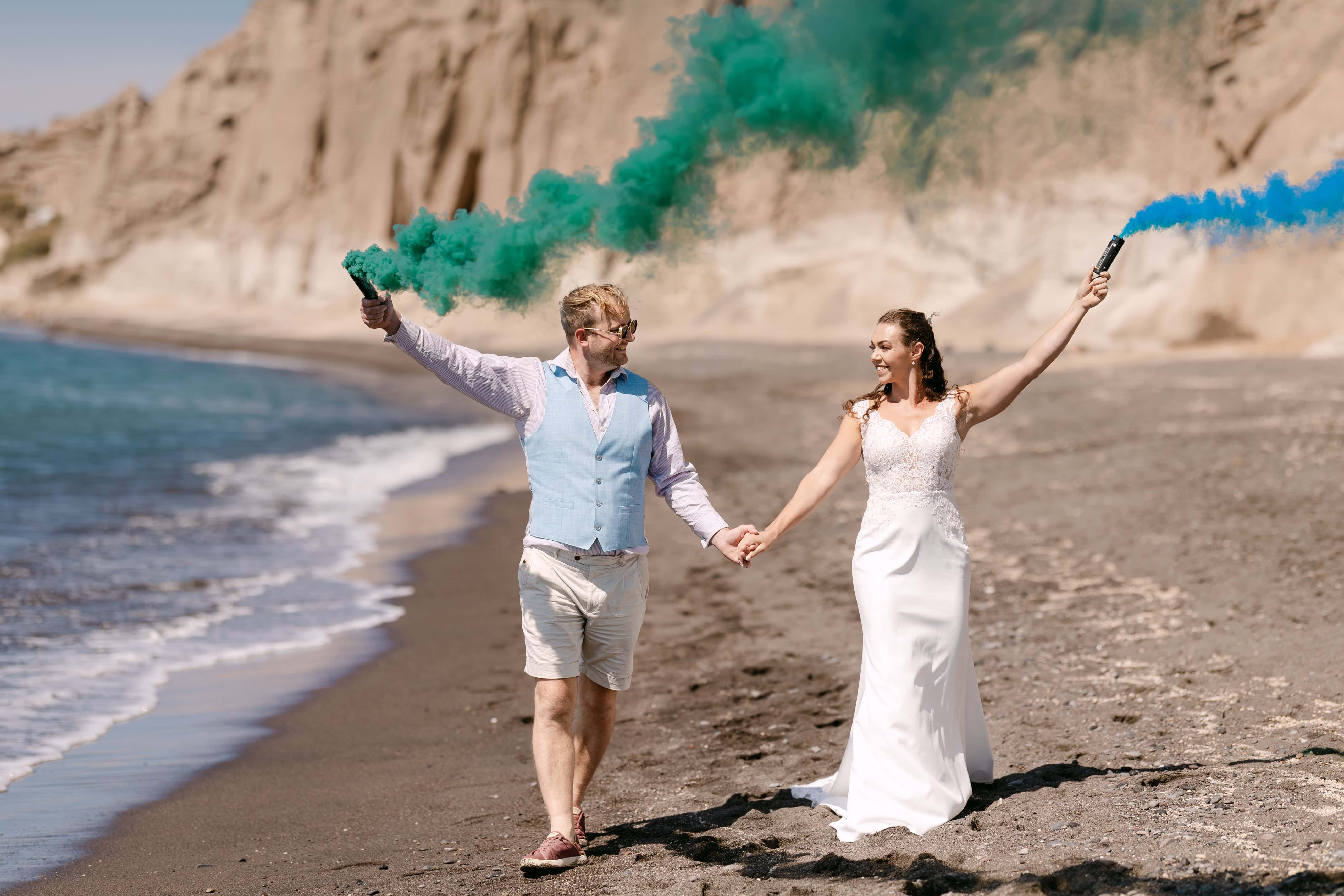 Bride and groom with smoke flares on beach