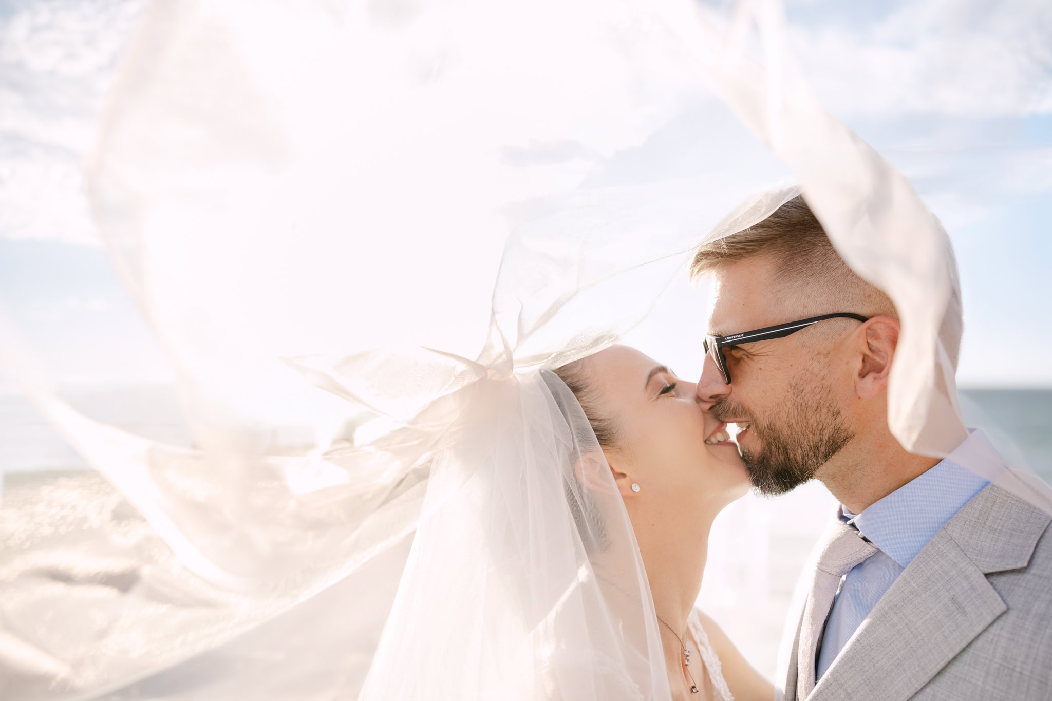 Bride and groom kissing beneath flowing veil in Marbella photographed by CG Weddings Photography