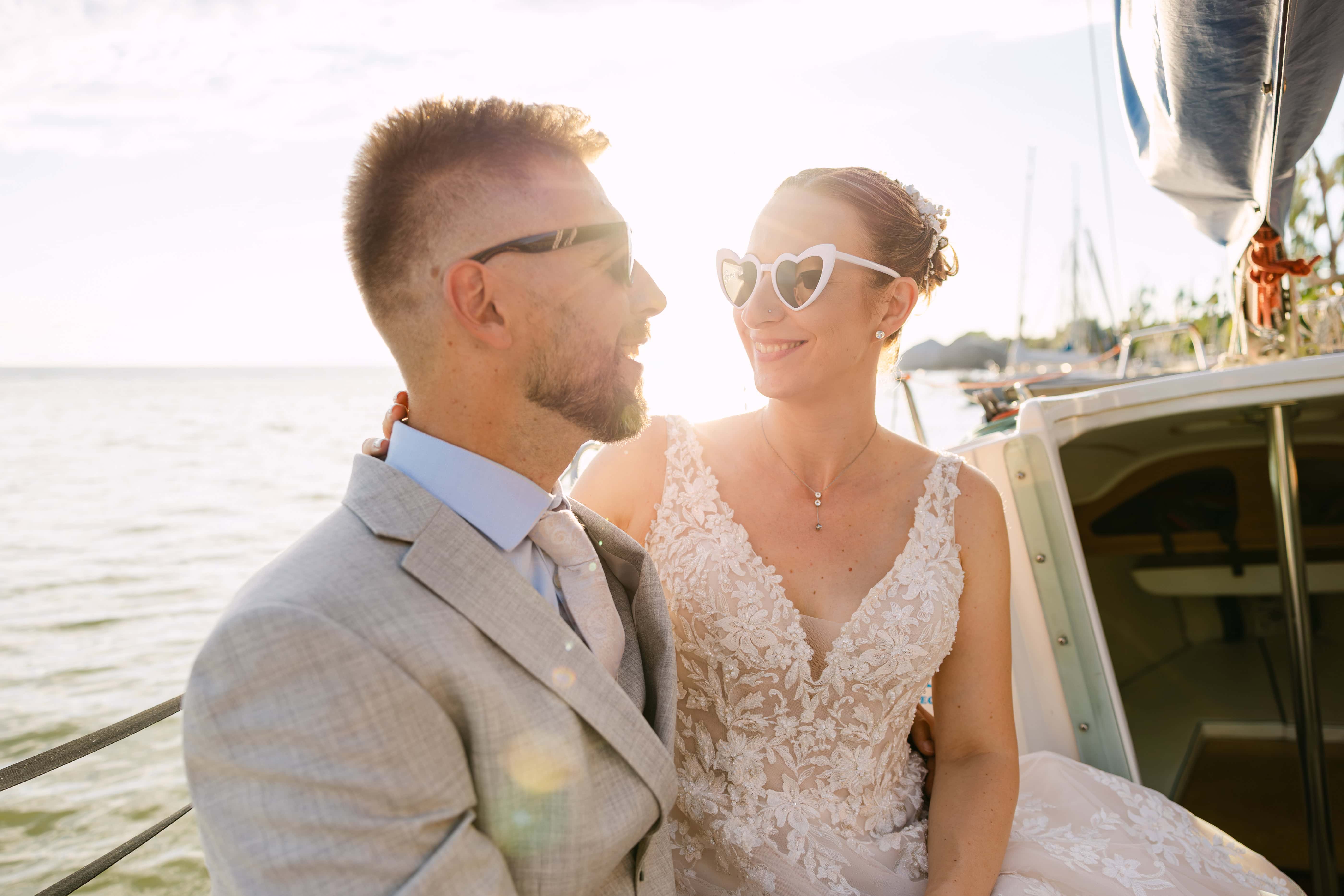 Bride and groom smiling on boat at sunset